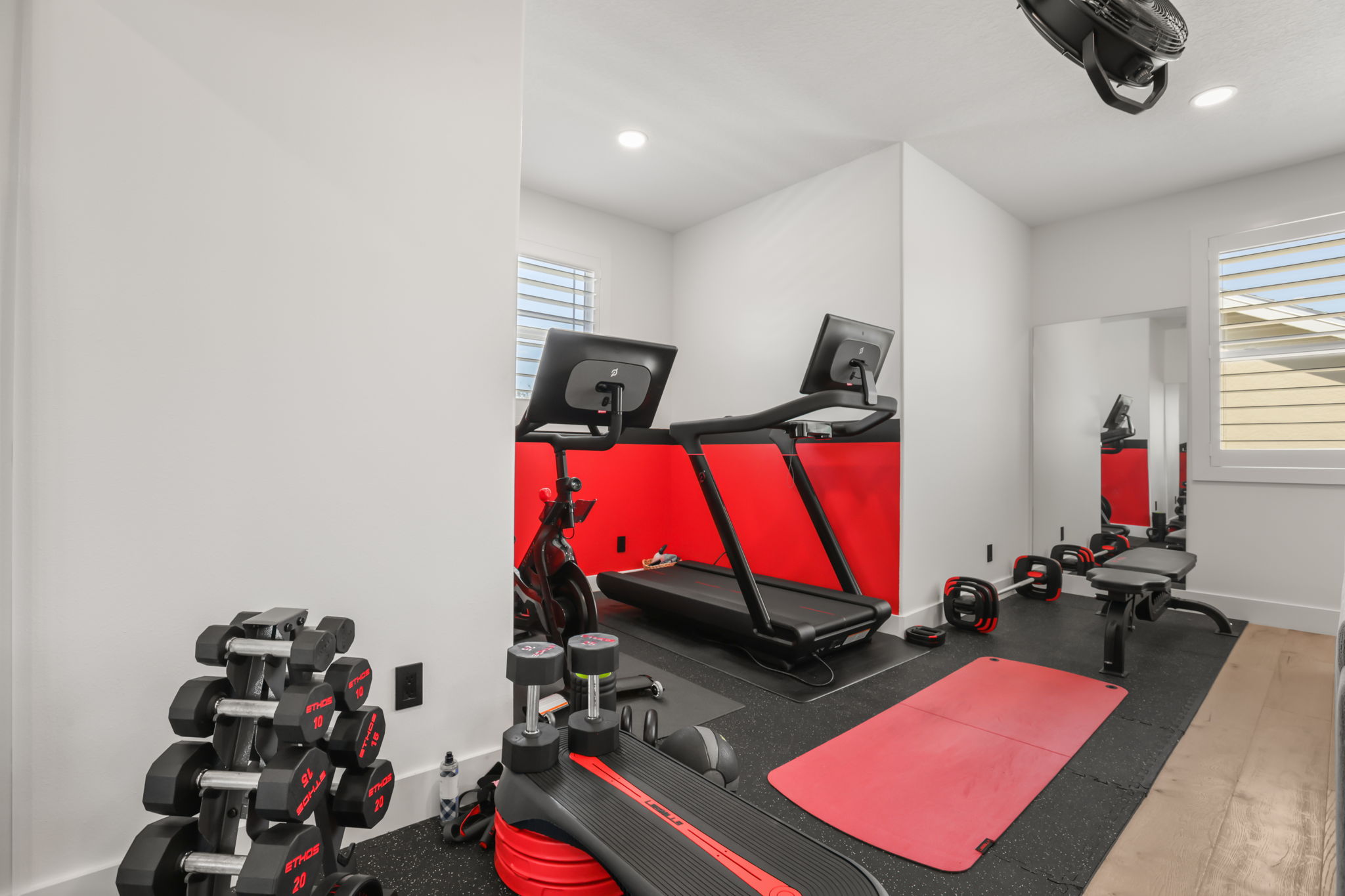 Gym with treadmill, dumbbells and red accent wall